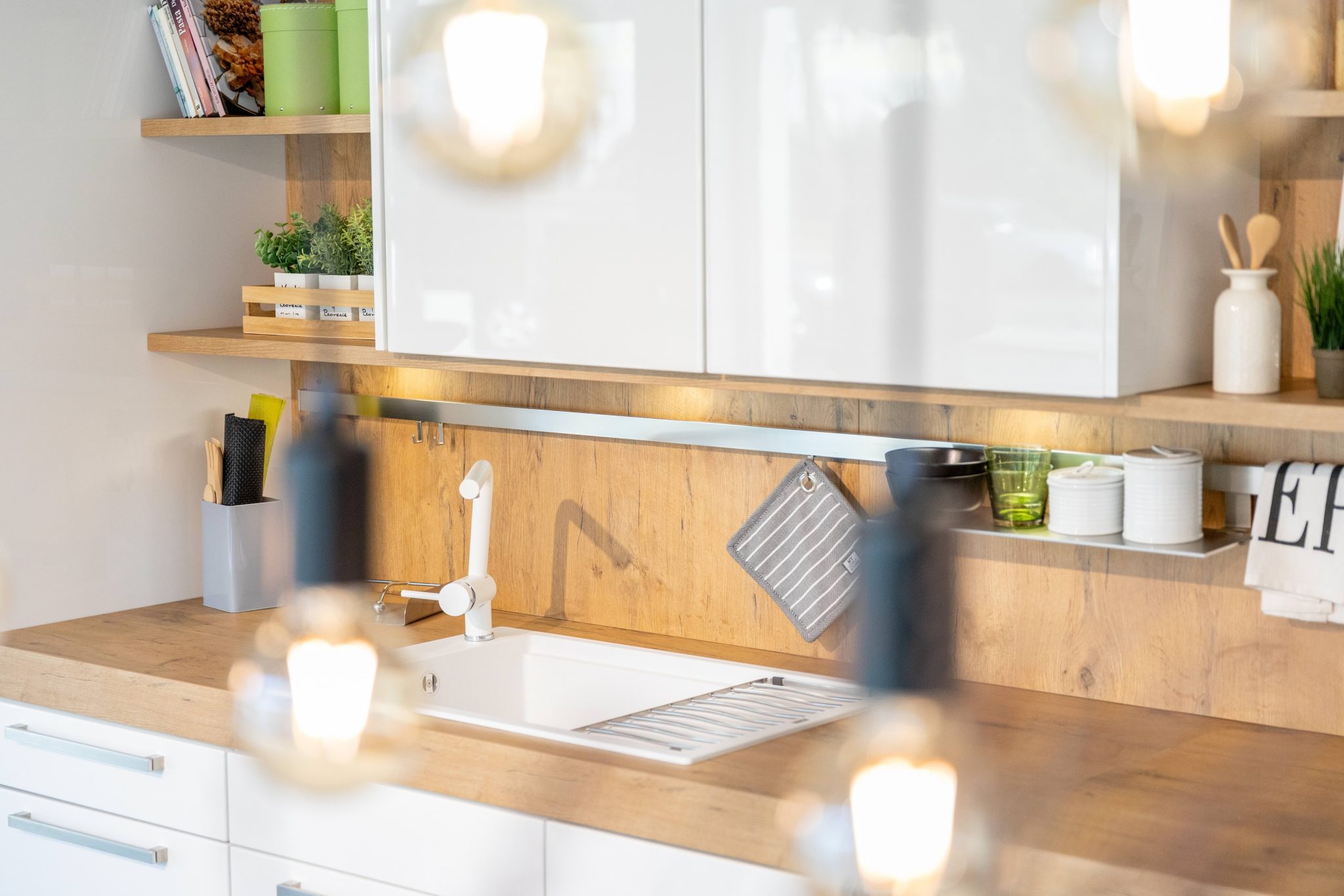 Radna ploča u drvenom izgledu s bijelim visokosjajnim zidnim ormarićima, bijeli sudoper